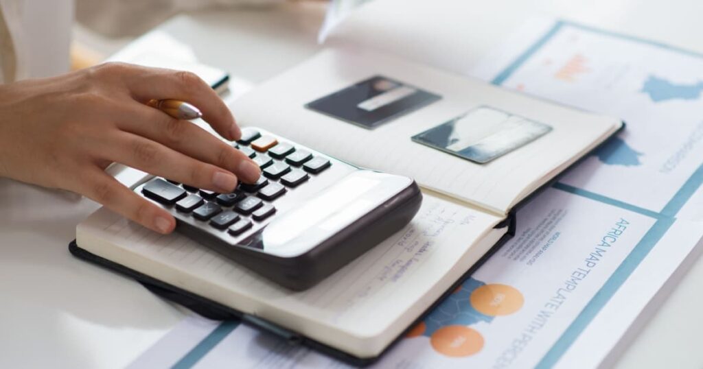 personne qui calcule sur un bureau à l'aide d'une calculatrice et d'un stylo dans la main 